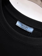 Prada【新品】2026SS春夏🆕 男女情侶款經典logo圖標設計短袖T卹簡約的時尚元素設計凸顯精簡,隸屬今夏高顏值單品. 客供優質針織棉面料,手感順滑細膩,著身的透氣舒適感無可挑剔.全新標誌皮質徽章縫製感染力強大,彰顯前衛獨特個性.時尚達人的必備單品.表達一絲不苟的時尚氣息. 顏色：白色黑色尺碼：S/M/L/XL/2XL S肩寬43胸圍104衣長67袖長21