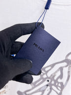 Prada【新品】2026SS春夏🆕 男女情侶款經典logo圖標設計短袖T卹簡約的時尚元素設計凸顯精簡,隸屬今夏高顏值單品. 客供優質針織棉面料,手感順滑細膩,著身的透氣舒適感無可挑剔.全新標誌皮質徽章縫製感染力強大,彰顯前衛獨特個性.時尚達人的必備單品.表達一絲不苟的時尚氣息. 顏色：白色黑色尺碼：S/M/L/XL/2XL S肩寬43胸圍104衣長67袖長21