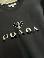 PRADA 普拉達2025秋冬新款設計感衛衣官網同步！這款T卹極簡主義設計和精美細節於一身。 Oversize飾邊引人聯想蒂羅爾著裝細節，召喚摩登新意，造就不同以往的概念化圖案，為傳統棉質T卹注入豐盈內涵。前幅圖形織帶車出的LOGO，別具一番特色，更顯品牌尊貴彰顯大牌風範，襯託出了極簡主義的設計風格，把優雅風展露的一覽無餘！ 作為一個追求設計感和裁剪工藝的品牌，用料永遠不會讓人失望！這款衫身採用索洛納棉混紡400 克布料，高貴精緻，布面棉質飽滿柔軟親膚總之這麼經典的款，秋冬必備！ M-4XL
