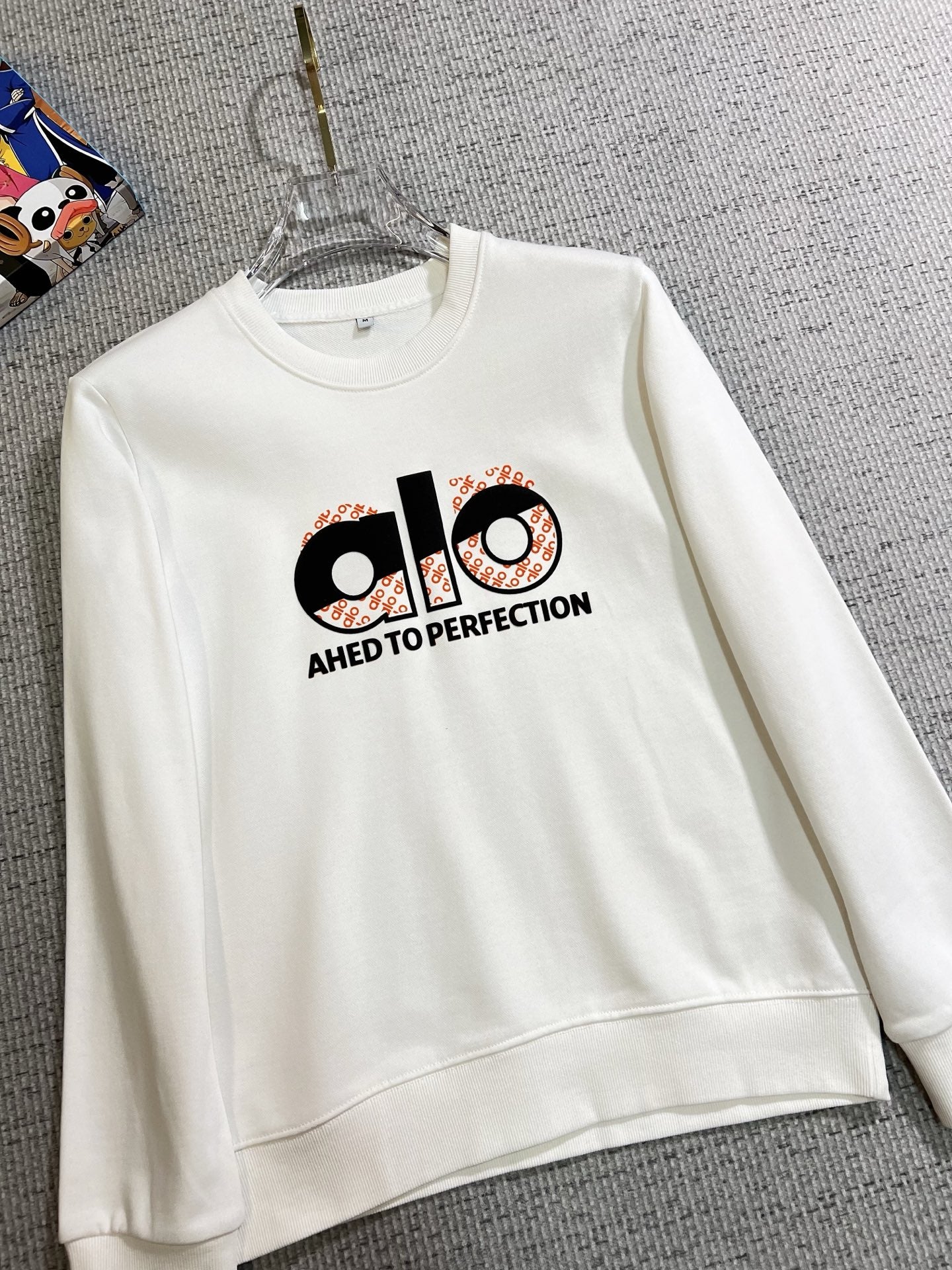 ALO 2025秋冬新款設計感衛衣官網同步！這款T卹極簡主義設計和精美細節於一身。 Oversize飾邊引人聯想蒂羅爾著裝細節，召喚摩登新意，造就不同以往的概念化圖案，為傳統棉質T卹注入豐盈內涵。前幅圖形織帶車出的LOGO，別具一番特色，更顯品牌尊貴彰顯大牌風範，襯託出了極簡主義的設計風格，把優雅風展露的一覽無餘！ 作為一個追求設計感和裁剪工藝的品牌，用料永遠不會讓人失望！這款衫身採用索洛納棉混紡400 克布料，高貴精緻，布面棉質飽滿柔軟親膚總之這麼經典的款，秋冬必備！ M-4XL