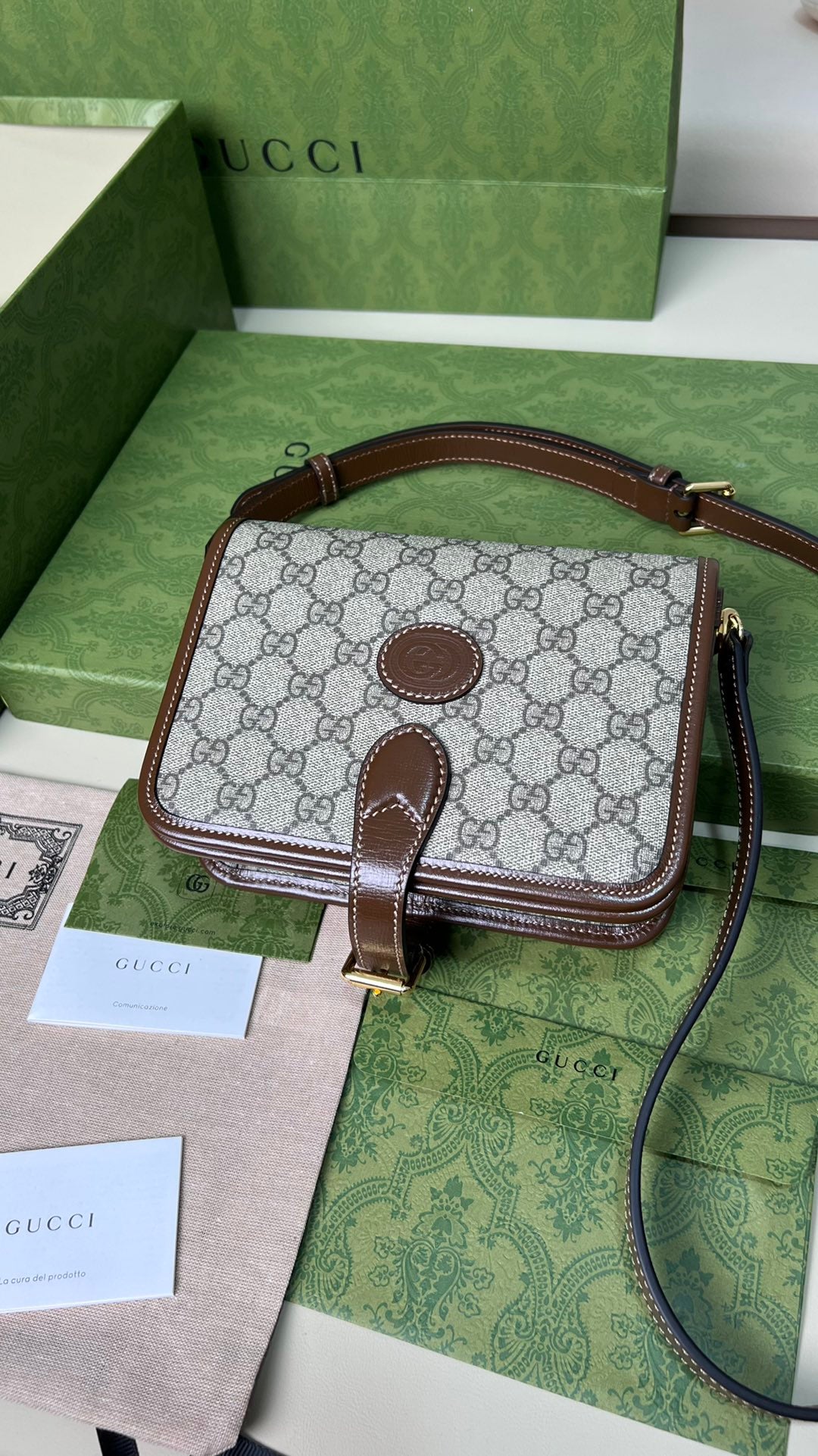 尺寸:20×17×8cm（26990898） Gucci海外通路資源特供男士郵差包❗️自問世以來，互扣式雙G一直都是品牌的標誌性元素之一。耳熟能詳的品牌象徵與皮革細節相融匯，讓這款單肩背包成為矚目的焦點。採用米色和烏木色GG Supreme 帆布，棕色皮革滾邊、棉麻襯裡，經典雙G字母交織帆布材質令整款設計散發出強烈的品牌內涵。