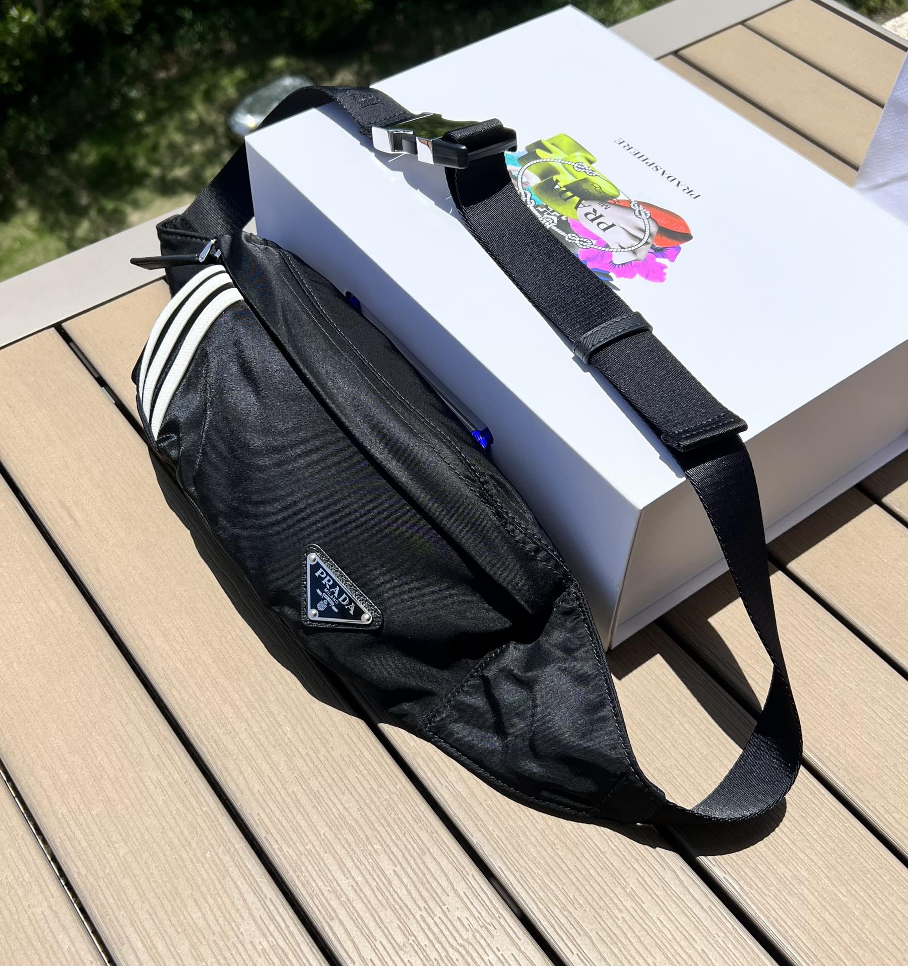可調式尼龍腰帶和側面插扣，拉鍊開合琺瑯金屬三角形標誌與adidas Re -Nylon 徽標