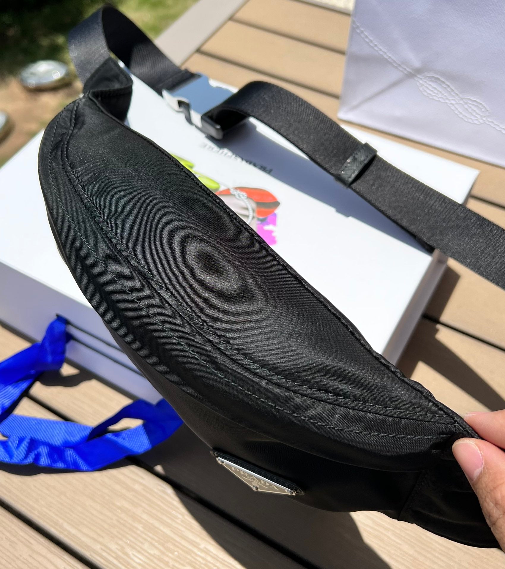 可調式尼龍腰帶和側面插扣，拉鍊開合琺瑯金屬三角形標誌與adidas Re -Nylon 徽標