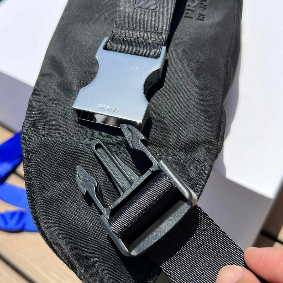 可調式尼龍腰帶和側面插扣，拉鍊開合琺瑯金屬三角形標誌與adidas Re -Nylon 徽標