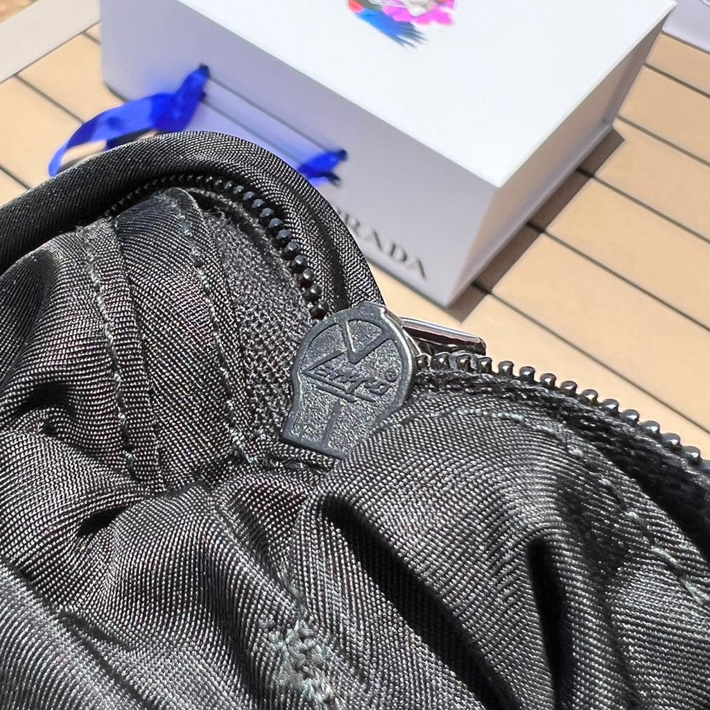 可調式尼龍腰帶和側面插扣，拉鍊開合琺瑯金屬三角形標誌與adidas Re -Nylon 徽標
