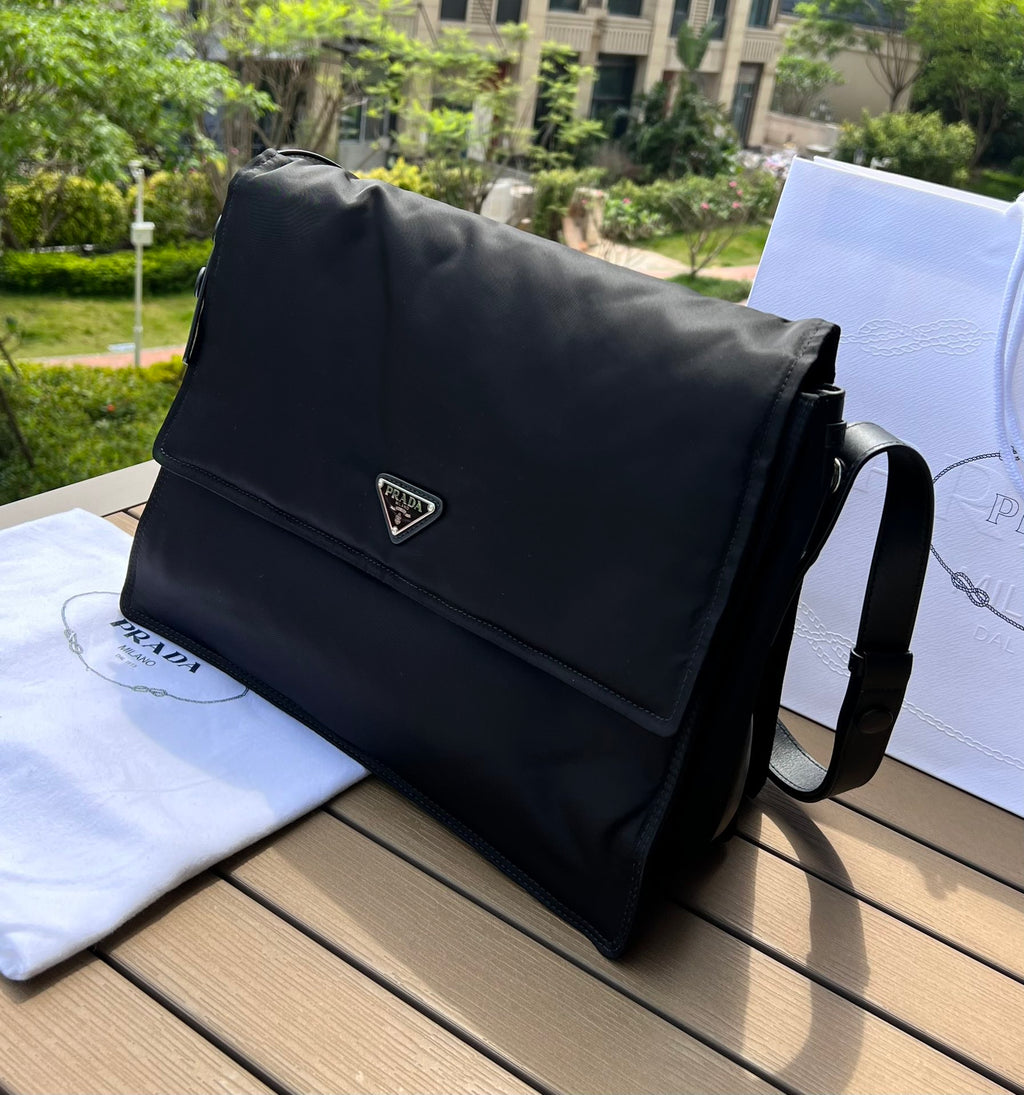 大尺寸:36×28×14cm（091250898） PRADA通路資源特供尼龍郵差包❗️選用Re-Nylon 再生尼龍材質打造。永續材質的應用象徵Prada 在布料的演進。翻蓋式包身配有可調式皮革肩帶，傳統與現代材質邂逅，造就都會優雅風格。背部拉鍊式口袋設計獨特功能性，翻蓋處飾以塗琺瑯金屬三角形徽標，鮮明醒目。磁扣式翻蓋開合，Re-Nylon 再生尼龍襯裡，配兩個口袋，其中一個帶拉鍊，極具有功能性和滿滿設計感