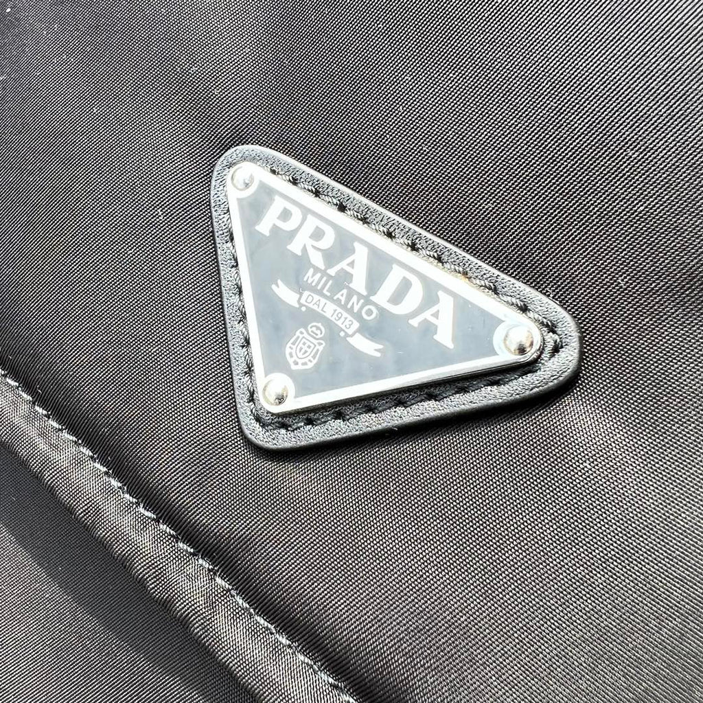 大尺寸:36×28×14cm（091250898） PRADA通路資源特供尼龍郵差包❗️選用Re-Nylon 再生尼龍材質打造。永續材質的應用象徵Prada 在布料的演進。翻蓋式包身配有可調式皮革肩帶，傳統與現代材質邂逅，造就都會優雅風格。背部拉鍊式口袋設計獨特功能性，翻蓋處飾以塗琺瑯金屬三角形徽標，鮮明醒目。磁扣式翻蓋開合，Re-Nylon 再生尼龍襯裡，配兩個口袋，其中一個帶拉鍊，極具有功能性和滿滿設計感