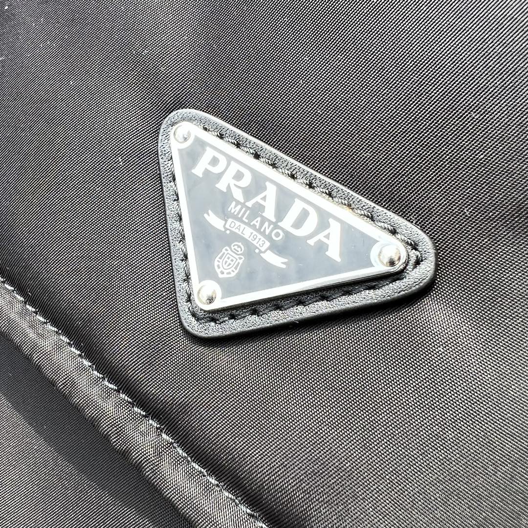 大尺寸:36×28×14cm（091250898） PRADA通路資源特供尼龍郵差包❗️選用Re-Nylon 再生尼龍材質打造。永續材質的應用象徵Prada 在布料的演進。翻蓋式包身配有可調式皮革肩帶，傳統與現代材質邂逅，造就都會優雅風格。背部拉鍊式口袋設計獨特功能性，翻蓋處飾以塗琺瑯金屬三角形徽標，鮮明醒目。磁扣式翻蓋開合，Re-Nylon 再生尼龍襯裡，配兩個口袋，其中一個帶拉鍊，極具有功能性和滿滿設計感
