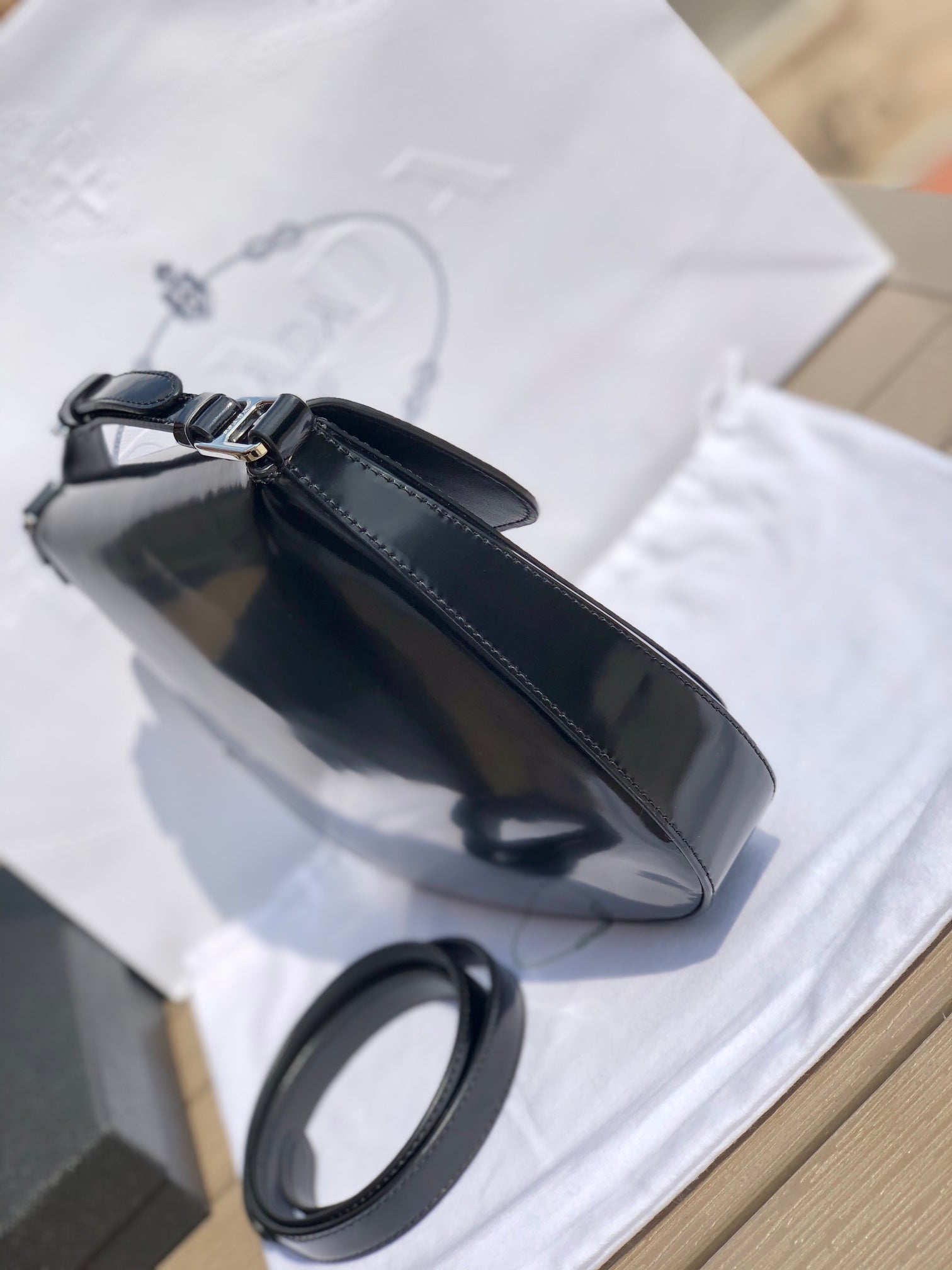 尺寸：19*6*24cm（56980898）PRADA代工廠出品翻蓋腋下包❗️普拉達這款精緻的Prada Cleo手袋重新詮釋品牌標誌性的復古設計。底部和側面獨特的傾斜結構彰顯這款翻蓋手袋簡約的弧形線條，賦予其輕盈柔和的造型風格。 Prada系列別緻的亮面皮革材質頗具現代感與多變風格，慣於創造嶄新的組合與對比效果。琺瑯三角形標誌呈現鮮明的品牌格調。磁扣扣合Prada標誌尼龍襯裡，配上貼布口袋。可延長皮革提把，可將單肩包變成斜背包！