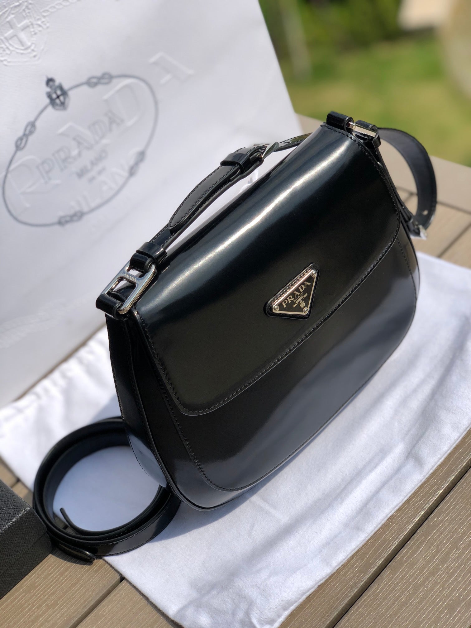 尺寸：19*6*24cm（56980898）PRADA代工廠出品翻蓋腋下包❗️普拉達這款精緻的Prada Cleo手袋重新詮釋品牌標誌性的復古設計。底部和側面獨特的傾斜結構彰顯這款翻蓋手袋簡約的弧形線條，賦予其輕盈柔和的造型風格。 Prada系列別緻的亮面皮革材質頗具現代感與多變風格，慣於創造嶄新的組合與對比效果。琺瑯三角形標誌呈現鮮明的品牌格調。磁扣扣合Prada標誌尼龍襯裡，配上貼布口袋。可延長皮革提把，可將單肩包變成斜背包！