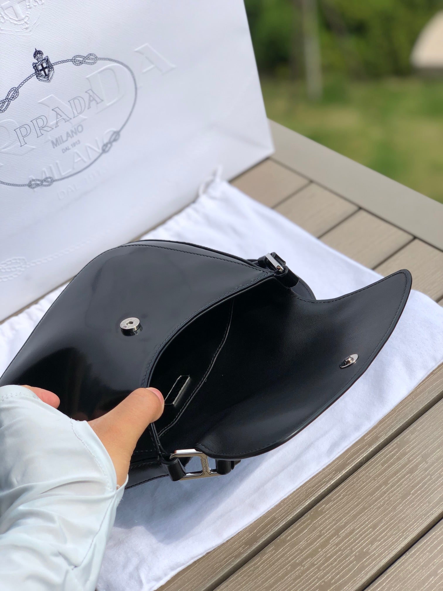 尺寸：19*6*24cm（56980898）PRADA代工廠出品翻蓋腋下包❗️普拉達這款精緻的Prada Cleo手袋重新詮釋品牌標誌性的復古設計。底部和側面獨特的傾斜結構彰顯這款翻蓋手袋簡約的弧形線條，賦予其輕盈柔和的造型風格。 Prada系列別緻的亮面皮革材質頗具現代感與多變風格，慣於創造嶄新的組合與對比效果。琺瑯三角形標誌呈現鮮明的品牌格調。磁扣扣合Prada標誌尼龍襯裡，配上貼布口袋。可延長皮革提把，可將單肩包變成斜背包！