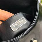 尺寸：19*6*24cm（56980898）PRADA代工廠出品翻蓋腋下包❗️普拉達這款精緻的Prada Cleo手袋重新詮釋品牌標誌性的復古設計。底部和側面獨特的傾斜結構彰顯這款翻蓋手袋簡約的弧形線條，賦予其輕盈柔和的造型風格。 Prada系列別緻的亮面皮革材質頗具現代感與多變風格，慣於創造嶄新的組合與對比效果。琺瑯三角形標誌呈現鮮明的品牌格調。磁扣扣合Prada標誌尼龍襯裡，配上貼布口袋。可延長皮革提把，可將單肩包變成斜背包！