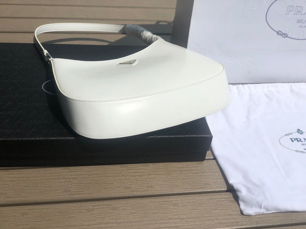 白色❗️尺寸：22*6*27cm（05850898）PRADA代工廠訂單出品腋下包❗️普拉達這款Prada Cleo單肩包重釋1990年代品牌標誌性的設計，頗具精緻格調。單肩包結構別緻，底部和側面漸顯圓潤，彰顯簡約的弧形線條，賦予其新月包風格的柔美輕盈外觀。 Prada系列中的亮面皮革材質現代而百搭，是打造全新組合與對比感的理想之選。三角形琺瑯標誌呈現不凡的品牌格調，亮面皮革材質皮革提手金屬配件，琺瑯三角形金屬徽標，磁扣扣合，Prada徽標尼龍襯裡，配貼布口袋