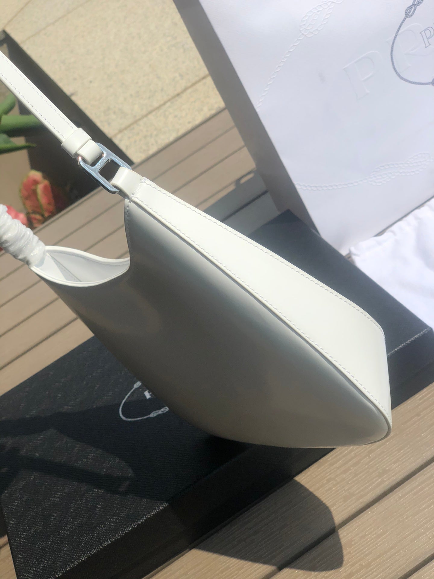 白色❗️尺寸：22*6*27cm（05850898）PRADA代工廠訂單出品腋下包❗️普拉達這款Prada Cleo單肩包重釋1990年代品牌標誌性的設計，頗具精緻格調。單肩包結構別緻，底部和側面漸顯圓潤，彰顯簡約的弧形線條，賦予其新月包風格的柔美輕盈外觀。 Prada系列中的亮面皮革材質現代而百搭，是打造全新組合與對比感的理想之選。三角形琺瑯標誌呈現不凡的品牌格調，亮面皮革材質皮革提手金屬配件，琺瑯三角形金屬徽標，磁扣扣合，Prada徽標尼龍襯裡，配貼布口袋