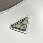 白色❗️尺寸：22*6*27cm（05850898）PRADA代工廠訂單出品腋下包❗️普拉達這款Prada Cleo單肩包重釋1990年代品牌標誌性的設計，頗具精緻格調。單肩包結構別緻，底部和側面漸顯圓潤，彰顯簡約的弧形線條，賦予其新月包風格的柔美輕盈外觀。 Prada系列中的亮面皮革材質現代而百搭，是打造全新組合與對比感的理想之選。三角形琺瑯標誌呈現不凡的品牌格調，亮面皮革材質皮革提手金屬配件，琺瑯三角形金屬徽標，磁扣扣合，Prada徽標尼龍襯裡，配貼布口袋