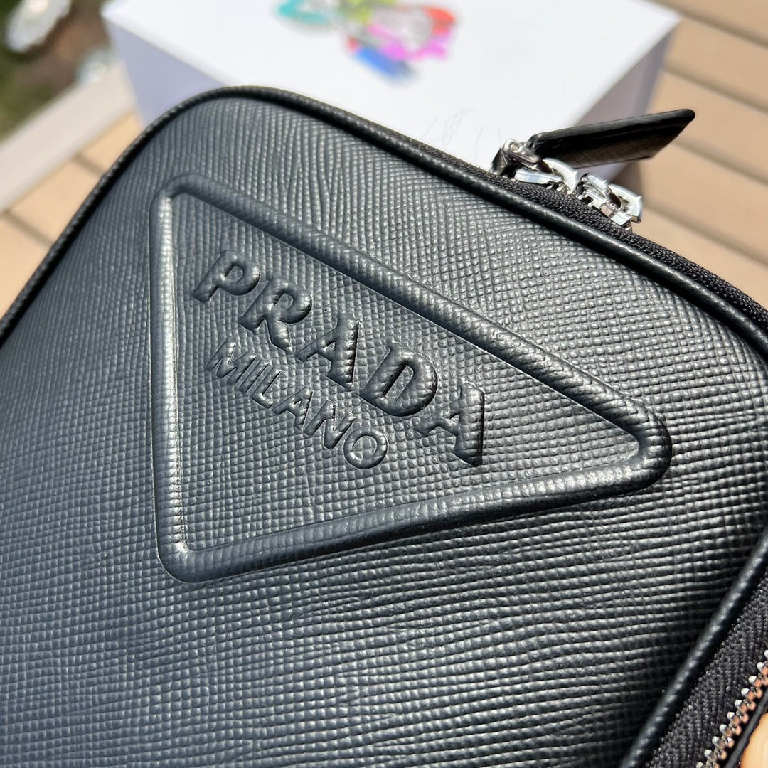 尺寸:19×16×5.5cm（581150898） PRADA通路資源特供訂單❗️Saffiano皮革壓花標誌手機包，採用普拉達標誌性的Saffiano 皮革，呈現別緻的交叉平行線陰影紋理和塗蠟飾面。 Prada 富有像徵意義的三角形標誌化身大幅壓花細節鋪陳於正面。背面塗琺瑯金屬三角形標誌，拉鍊開合，RE-Nylon 再生尼龍襯裡，可拆卸調價刺繡織帶肩帶