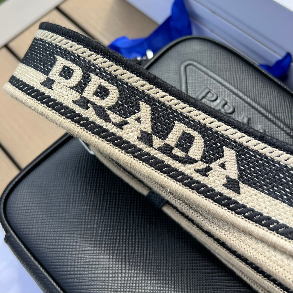 尺寸:19×16×5.5cm（581150898） PRADA通路資源特供訂單❗️Saffiano皮革壓花標誌手機包，採用普拉達標誌性的Saffiano 皮革，呈現別緻的交叉平行線陰影紋理和塗蠟飾面。 Prada 富有像徵意義的三角形標誌化身大幅壓花細節鋪陳於正面。背面塗琺瑯金屬三角形標誌，拉鍊開合，RE-Nylon 再生尼龍襯裡，可拆卸調價刺繡織帶肩帶
