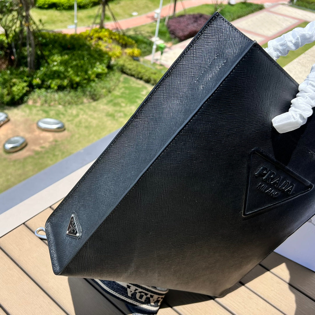 尺寸:37×35×7cm（111450898） PRADA通路資源特供訂單❗️男士托特包，這款時尚簡約的托特包取材品牌標誌性的Saffiano 皮革，呈現別緻的交叉平行線陰影紋理和塗蠟飾面。 Prada 富有像徵意義的三角形標誌化身大幅壓花細節，re-Nylon 再生尼龍襯裡，可拆卸調整刺繡織帶、皮革手柄！風格中性實用，整體設計簡約大方，搭配商務穿搭更有質感