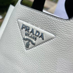 尺寸:18×15.5×10cm（56980898） PRADA通路資源特供菜籃❗️反向針跡彰顯這款手提包柔和圓潤的輪廓。包身飾以縫線工藝勾勒的三角形，藉由新穎設計重塑標誌性元素。 Prada 金屬刻字標誌點綴於中央，光澤閃耀，皮革手提，正面金屬刻字徽標，磁扣開合，軟羊革襯裡，配有三個隔層。通勤百搭！